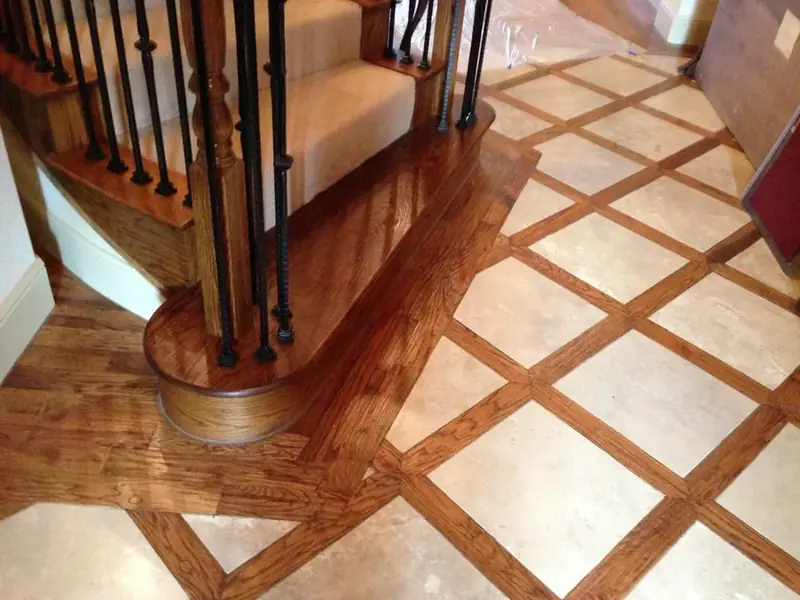 Custom hardwood border inlaid with tile at the foot of a staircase